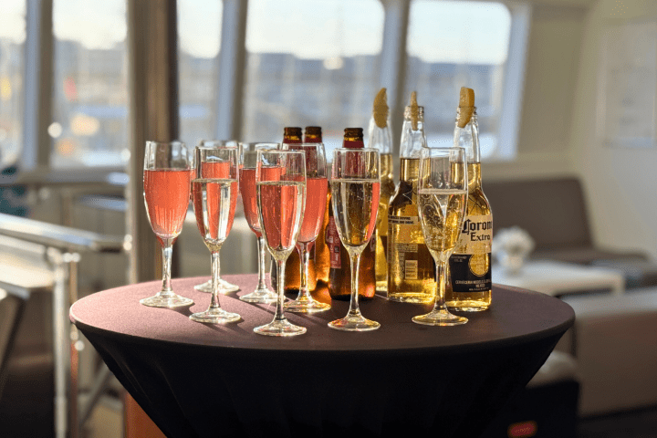 Glasses of pink champagne and beer bottles on a round table with a black cloth.