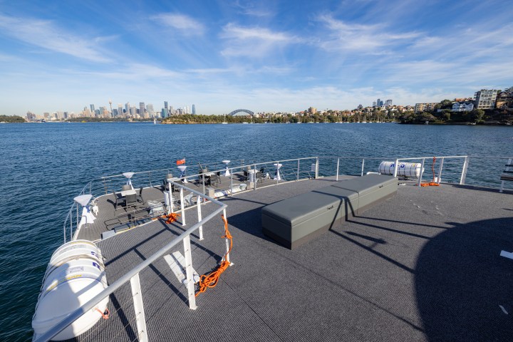 View of city skyline from a ferry deck with clear skies and waterfront.