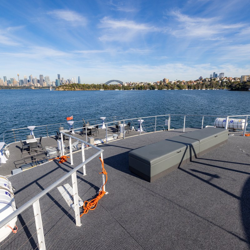 View of city skyline from a ferry deck with clear skies and waterfront.