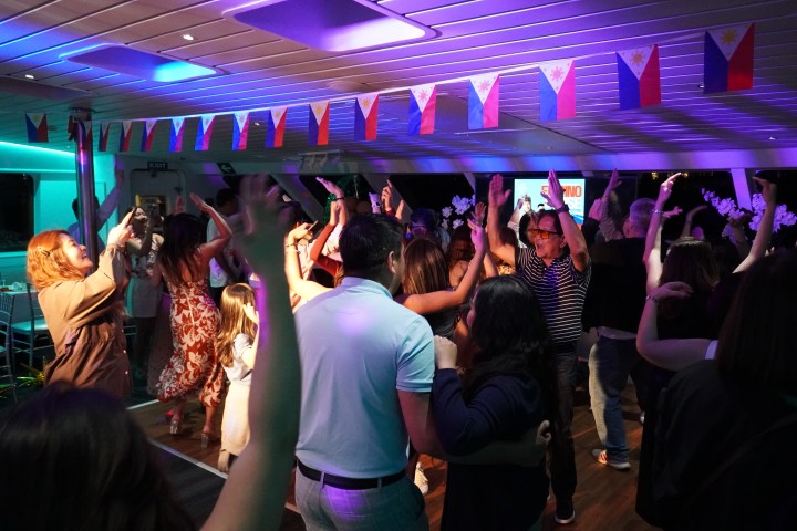 People dancing at a party with Philippine flags hanging overhead.