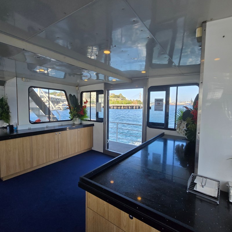 Interior of a boat with large windows, counter, and outdoor view.