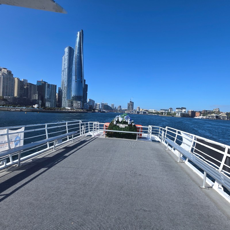 View from ferry deck of a city skyline with tall buildings by the water on a clear day.