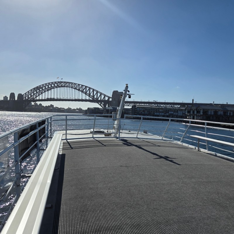 View of Sydney Harbour Bridge from a boat deck on a sunny day.