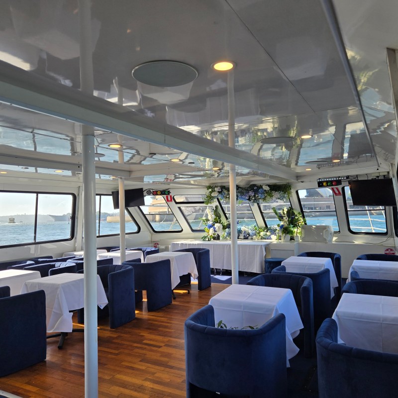 Interior of a boat with tables, chairs, and ocean view.