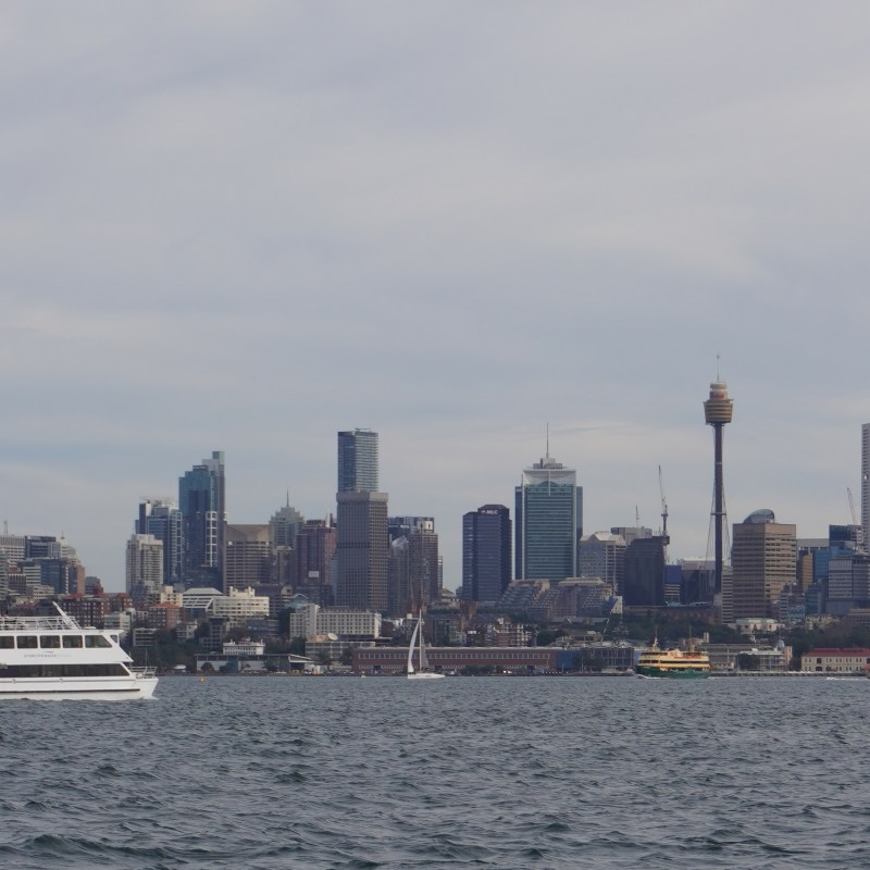 City skyline with a boat on the water in the foreground.